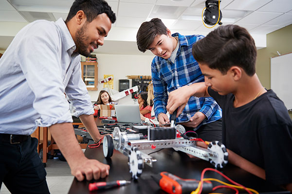 Students working on a robot under supervision.