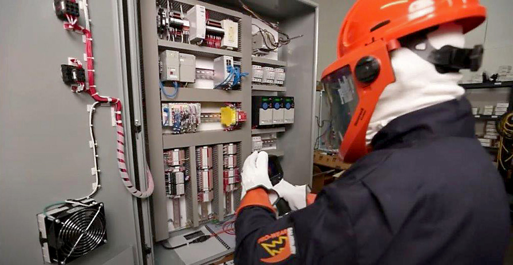 Student wearing proper safety equipment testing electrical panel.