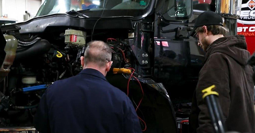 Mechanic and student going over a large truck engine repair