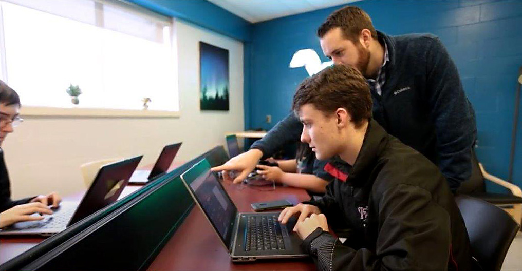 Instructor guiding a student using a computer at a desk