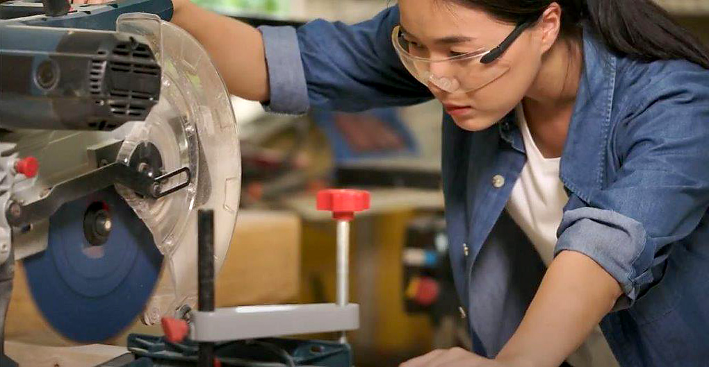 Female student using a mitre saw